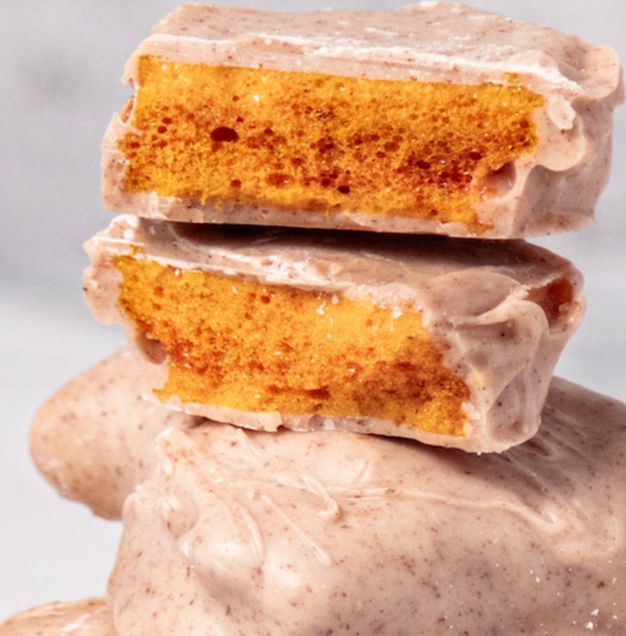 Lemon Cinnamon Honeycomb covered in white chocolate stacked on top of itself with one cut in half to show the airy center. 