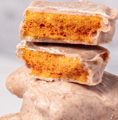 Lemon Cinnamon Honeycomb covered in white chocolate stacked on top of itself with one cut in half to show the airy center. 