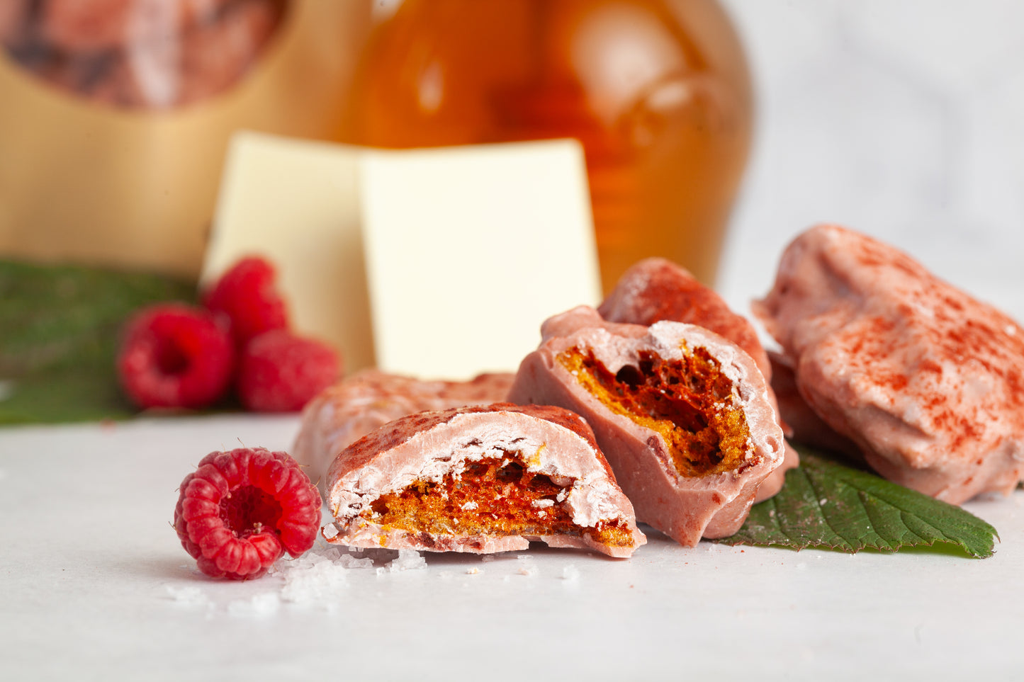 Raspberry Honeycomb candy cut in half to show the airy interior. Fresh raspberries and mint are also in the photo. 