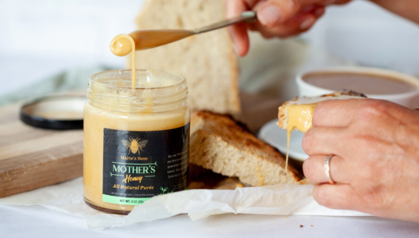 Mother's Honey a creamy honey on a knife with toast in the background. 