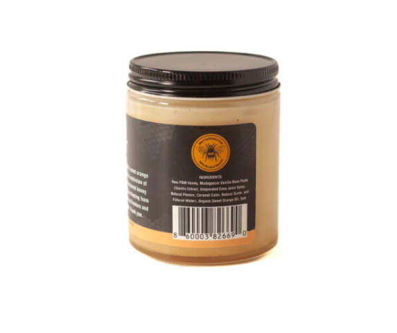 Orange Vanilla Creamed honey in a jar showing the label with the 100% Woman Owned Sticker, barcode and ingredients list. 