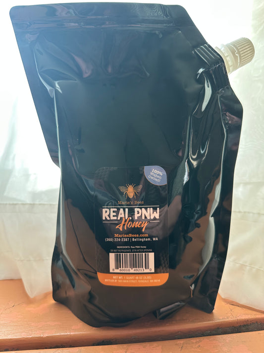A black Mylar squeeze pouch quart of raw honey with the label 'Real PNW Honey' and a barcode.